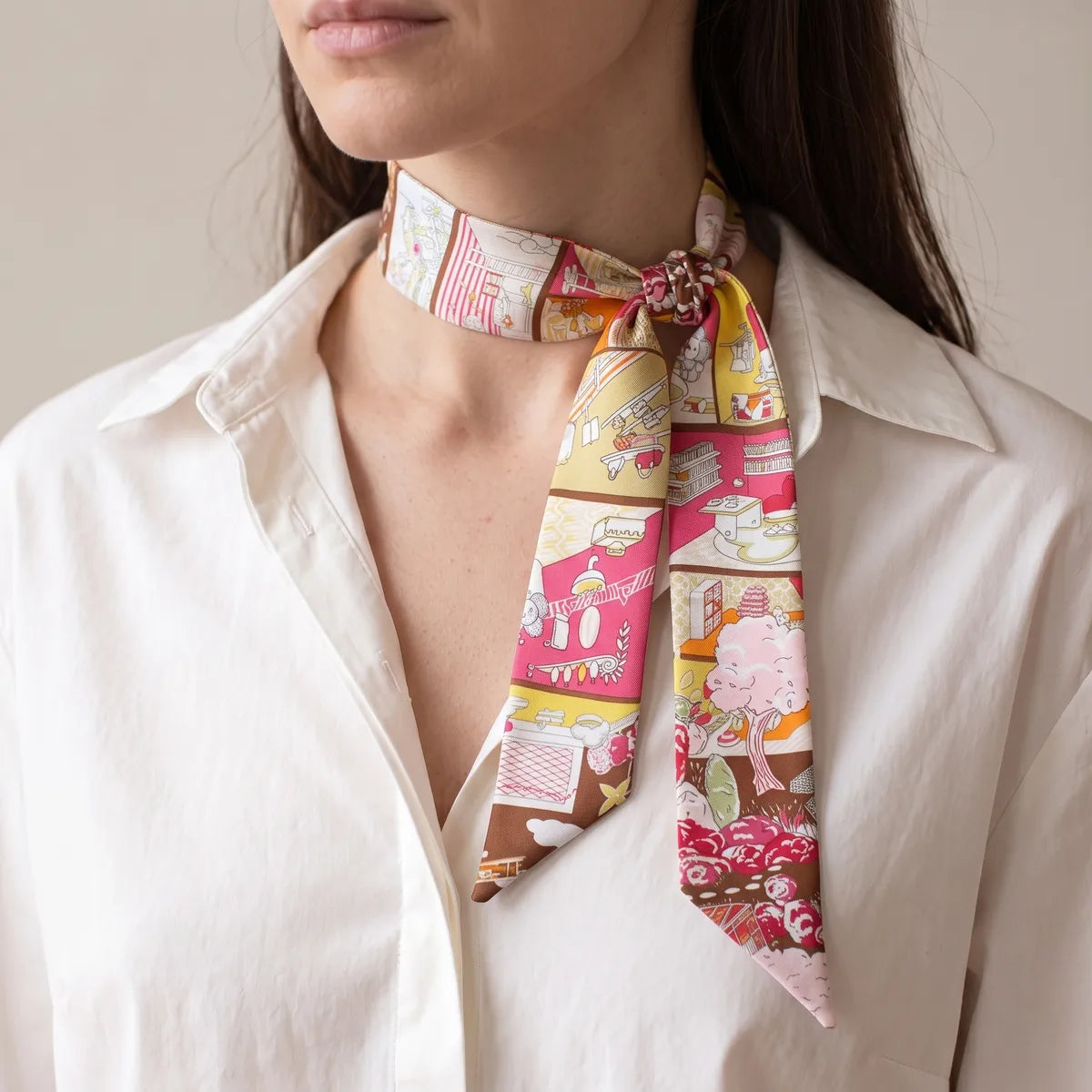 Hot pink house print skinny scarf knotted close to the collar on one side, worn with a white shirt