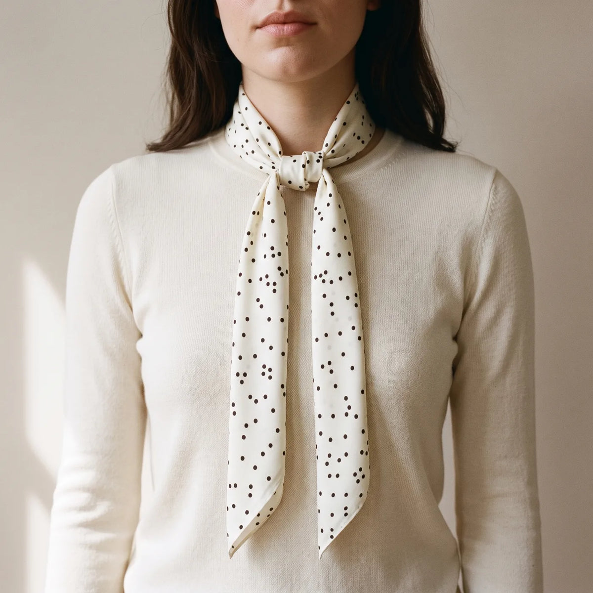 Cream polka dot silk square tied at the neck with long ends falling in front