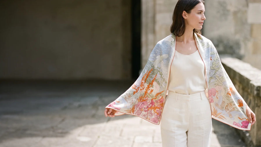 Woman holding a large blue garden print silk square open over her shoulders