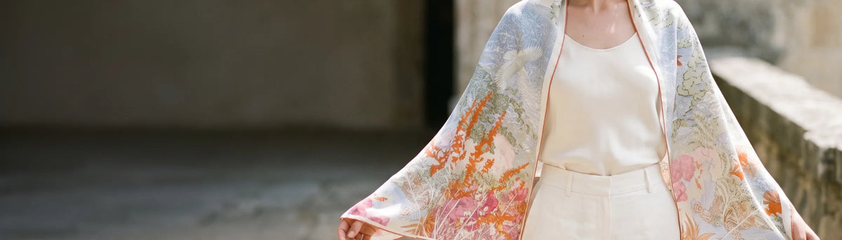 Woman holding a large blue garden print silk square open over her shoulders