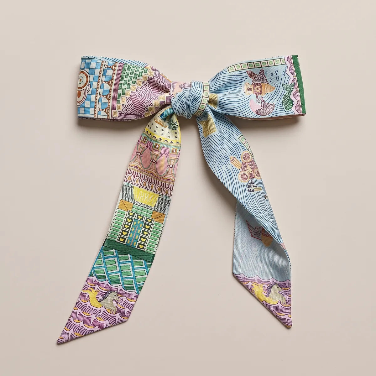 Light blue and lilac skinny silk and satin scarf tied in a flat bow, brickwork on one loop and wavy lines on the other
