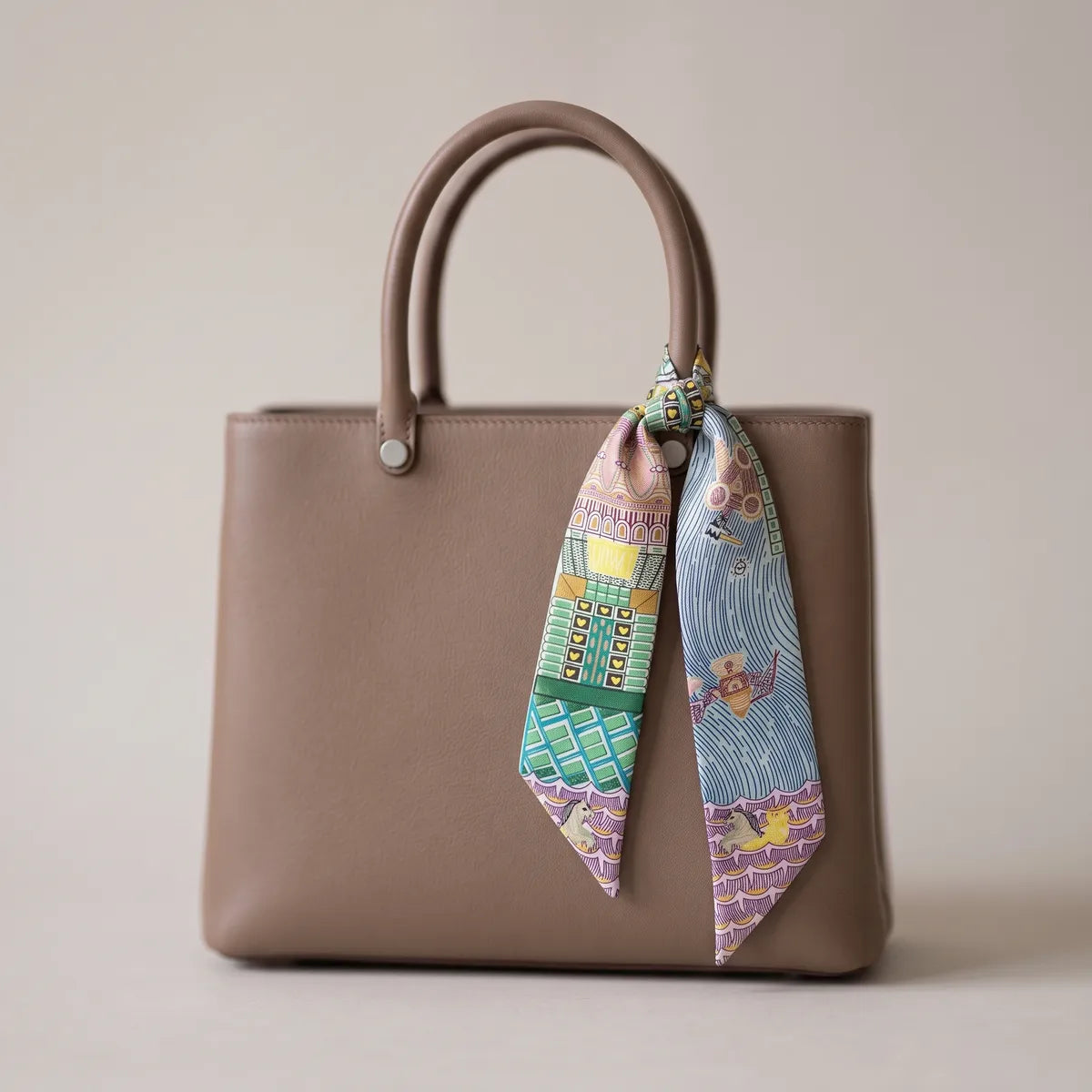 Light blue architecture skinny silk and satin scarf knotted on a taupe handbag, facades on one tail