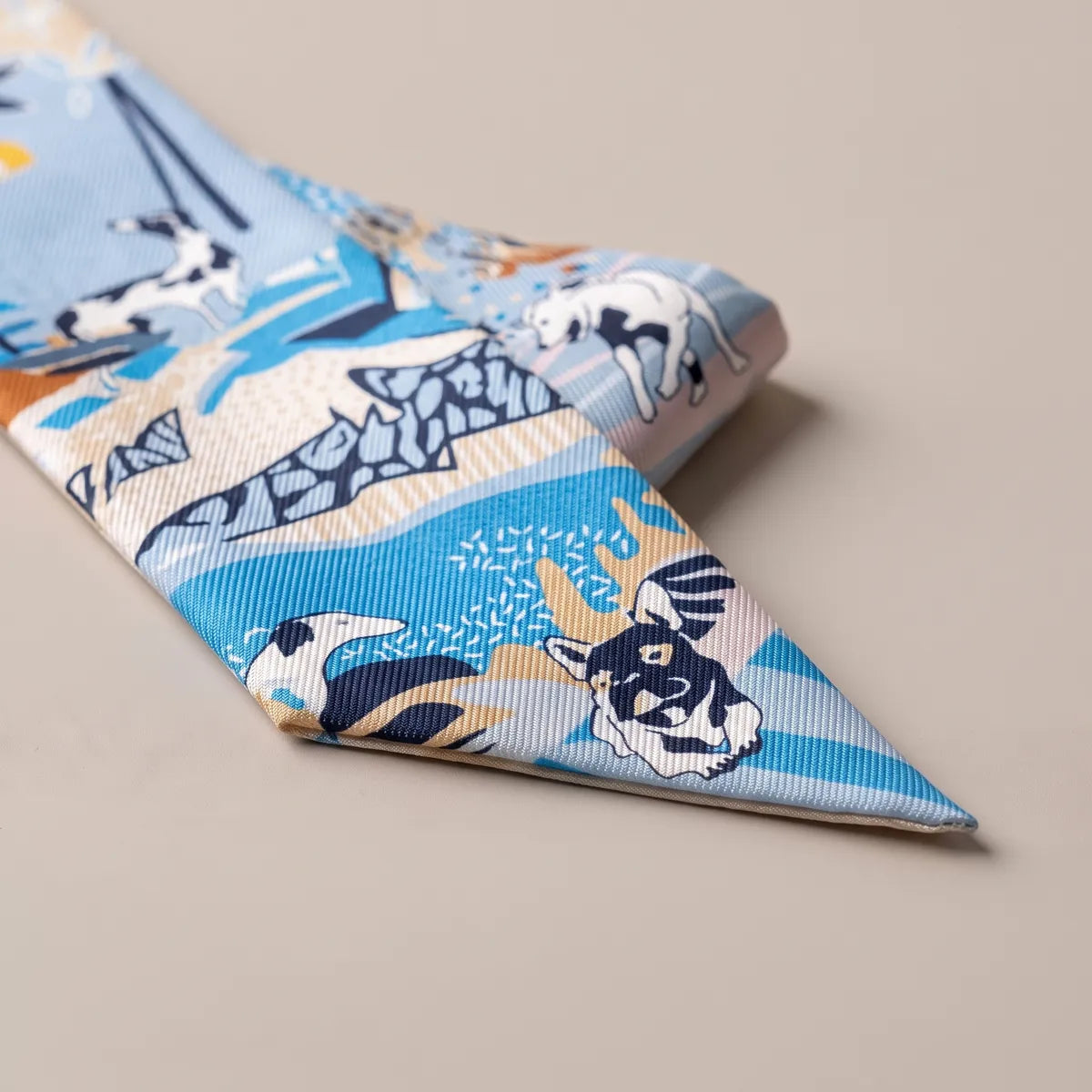 Folded tip of the light blue skinny scarf with a navy and white terrier face and blue stripes