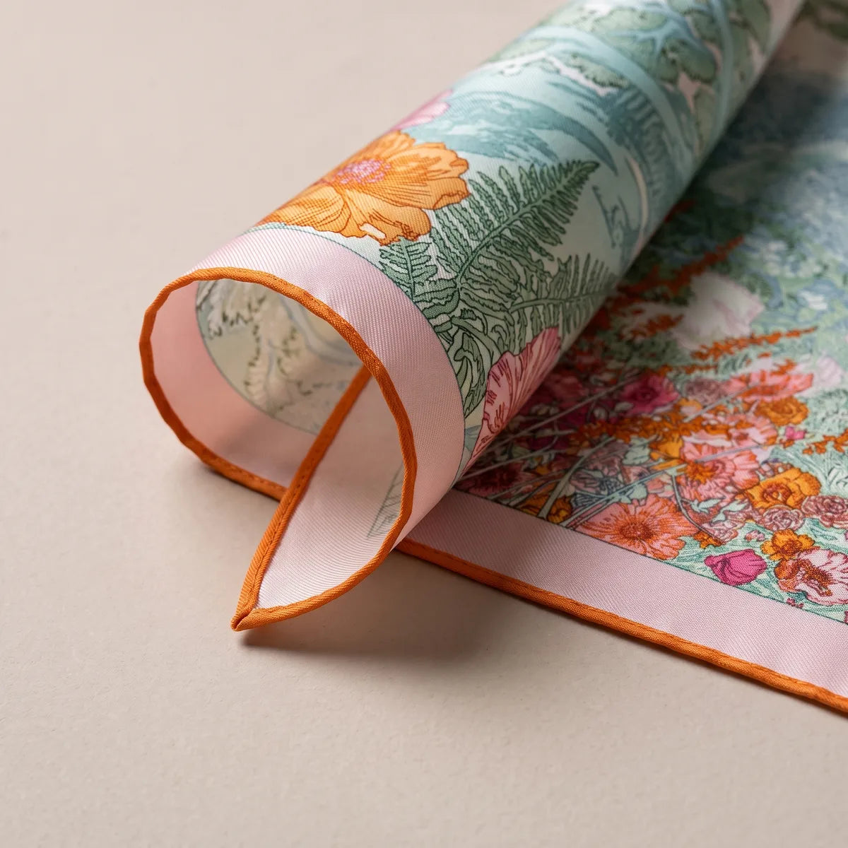 Rolled corner of the pastel garden scarf: a fern, orange flowers, pink band and orange edge