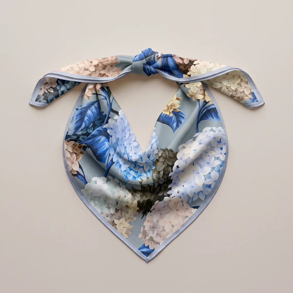 Hydrangea print bandana tied at the top and laid flat, blue leaves and pale flowers in the drape