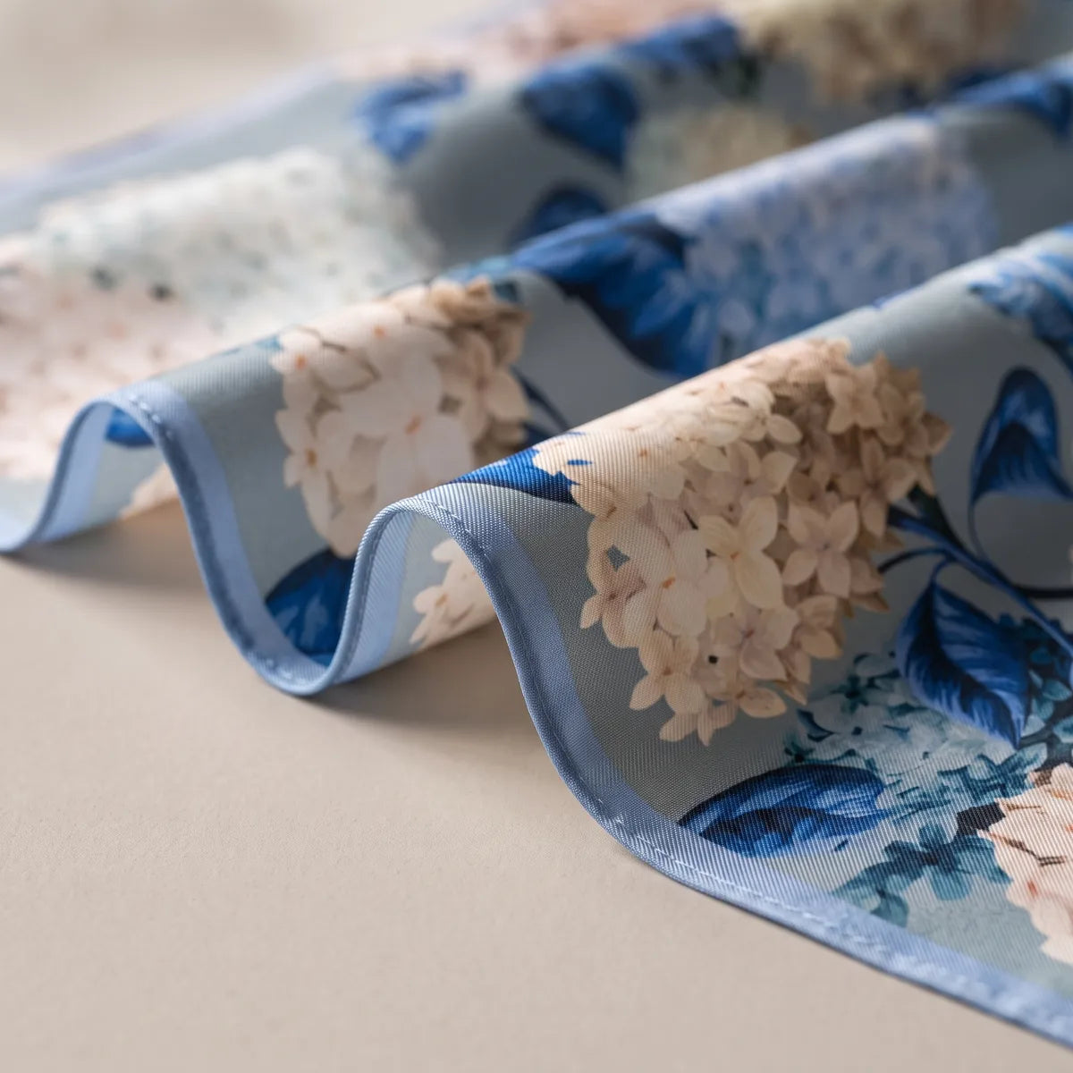 Soft folds of pale blue silk with blush hydrangea heads and a light blue hem