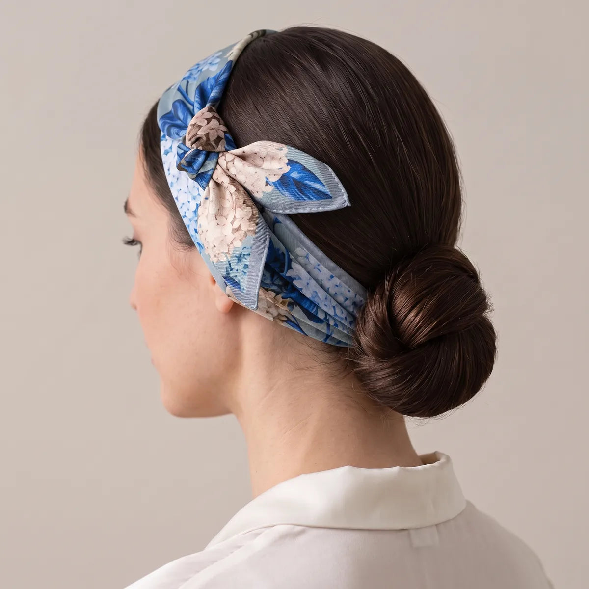 Hydrangea silk bandana worn as a headband with the knot above her ear and a smooth low bun behind