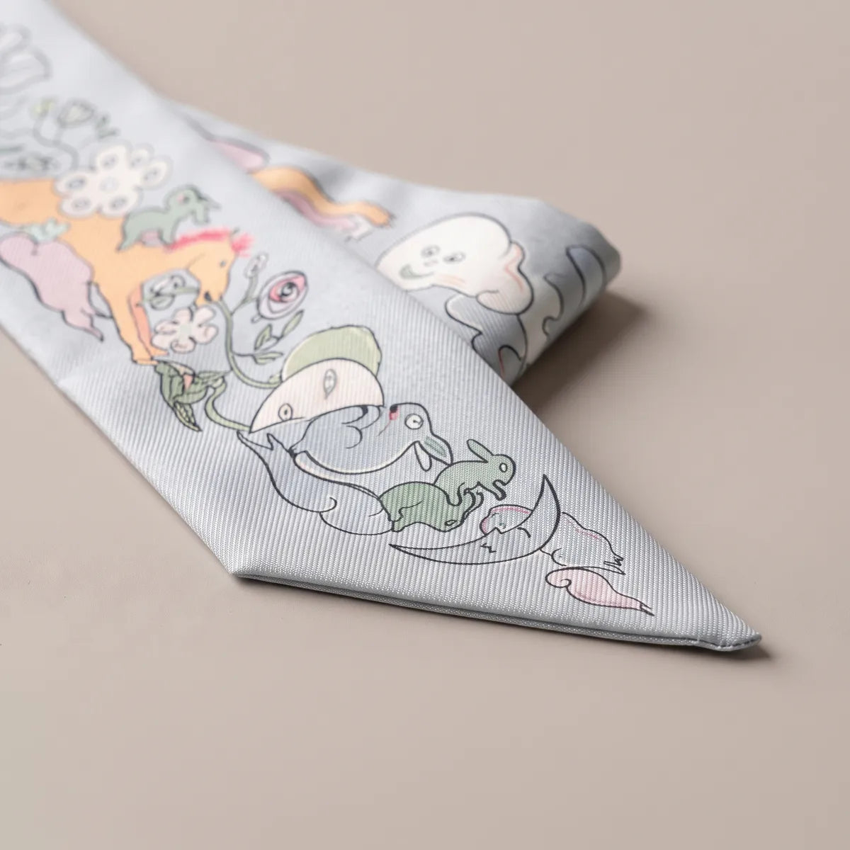 Tip of the light blue skinny scarf folded over: green rabbits sitting on a crescent moon, roses above