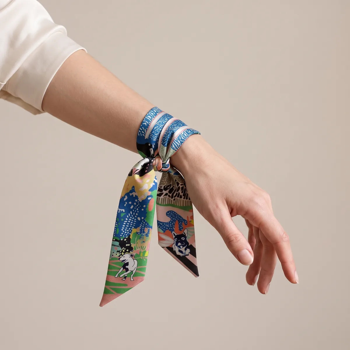 Jungle print skinny scarf wound around the wrist and tied, a terrier visible on one end