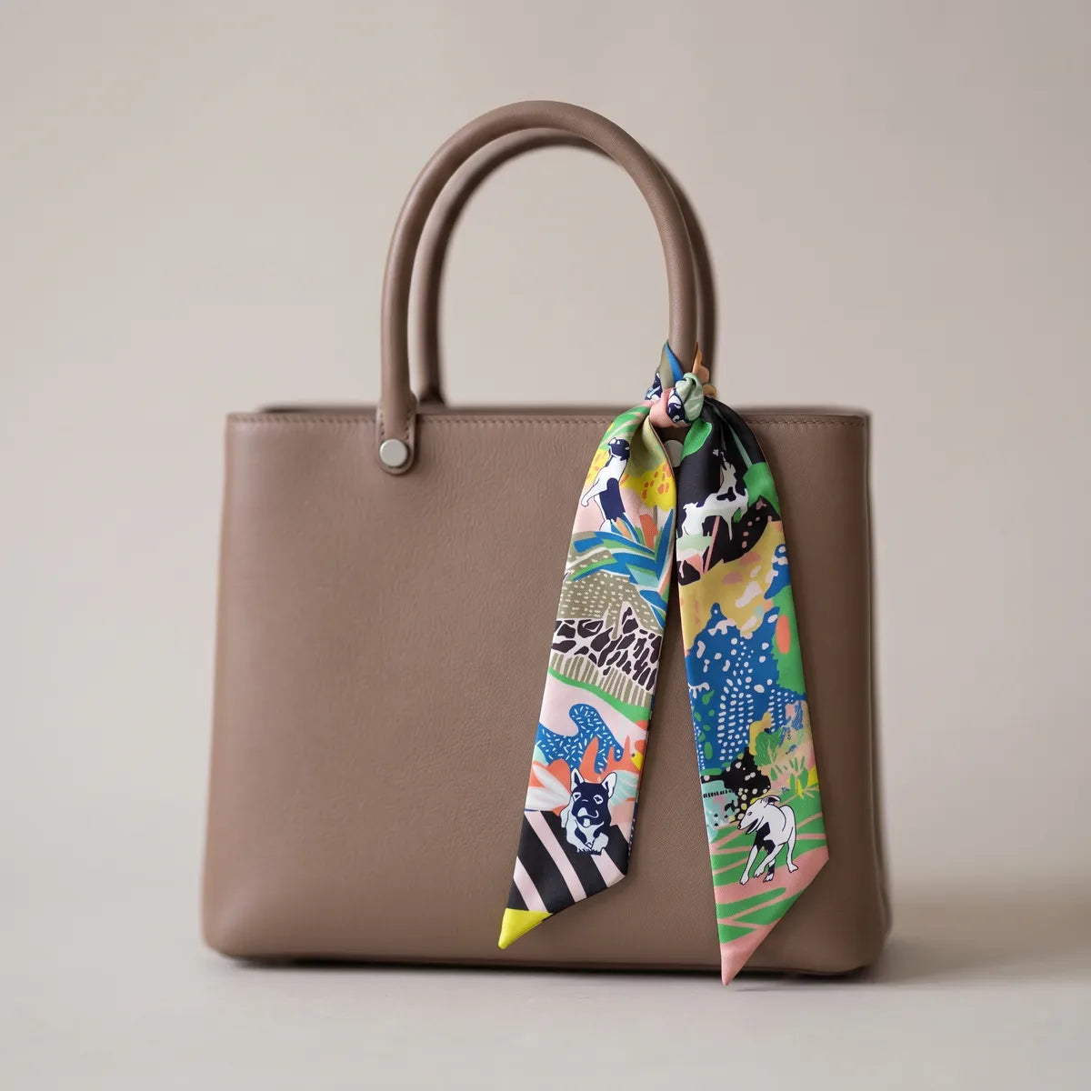 Multicolor terrier print skinny silk scarf knotted on a taupe leather bag handle
