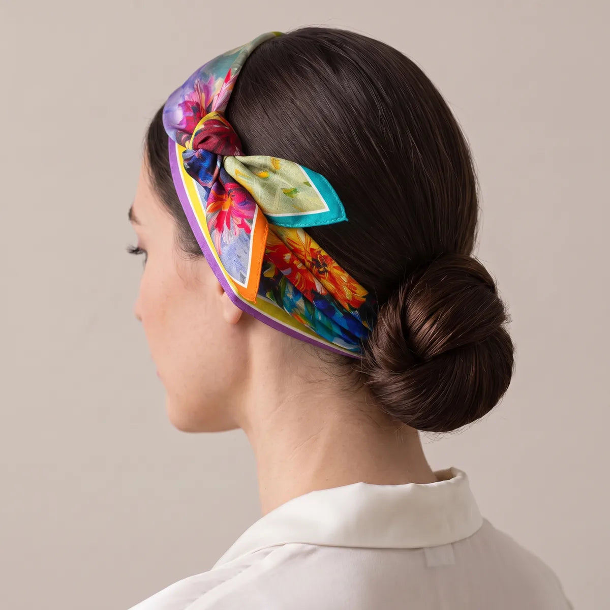 Bright floral bandana tied around the head as a headband, turquoise and orange tips at the knot above the ear