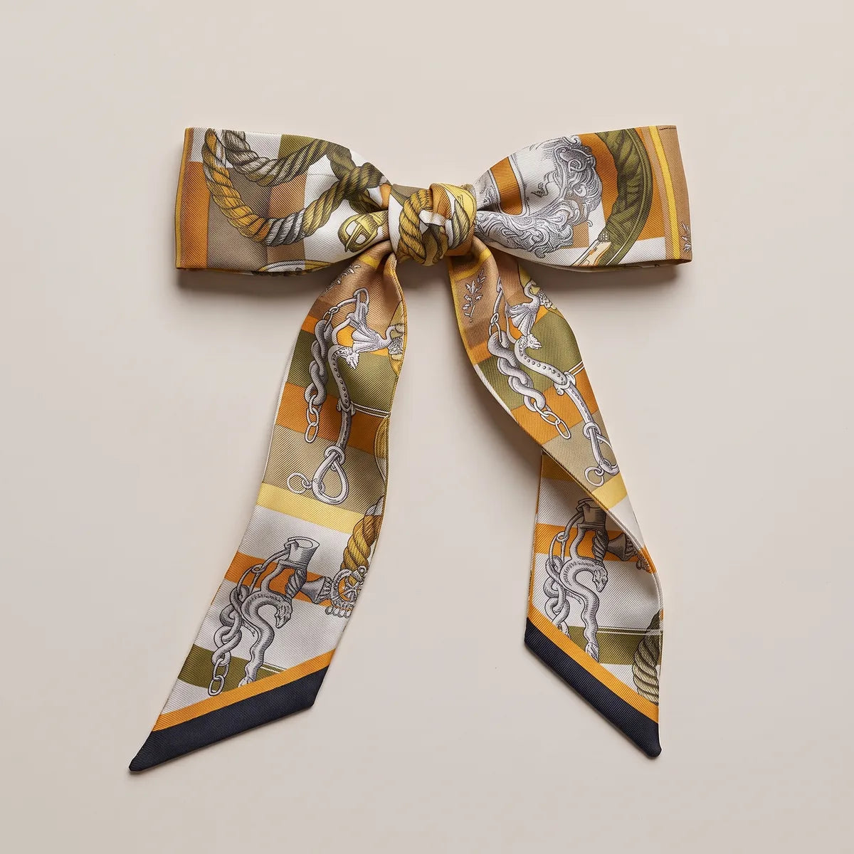 Mustard and olive skinny silk scarf tied in a bow, rope on the knot, ropes and a medallion on the loops
