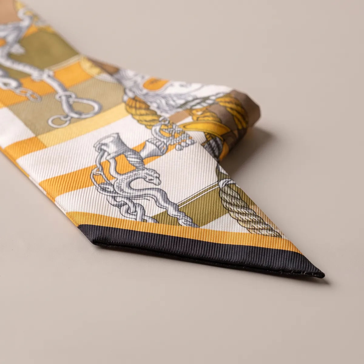 Navy tip of the mustard skinny scarf with a gray chain, a coiled serpent and a twist of yellow rope