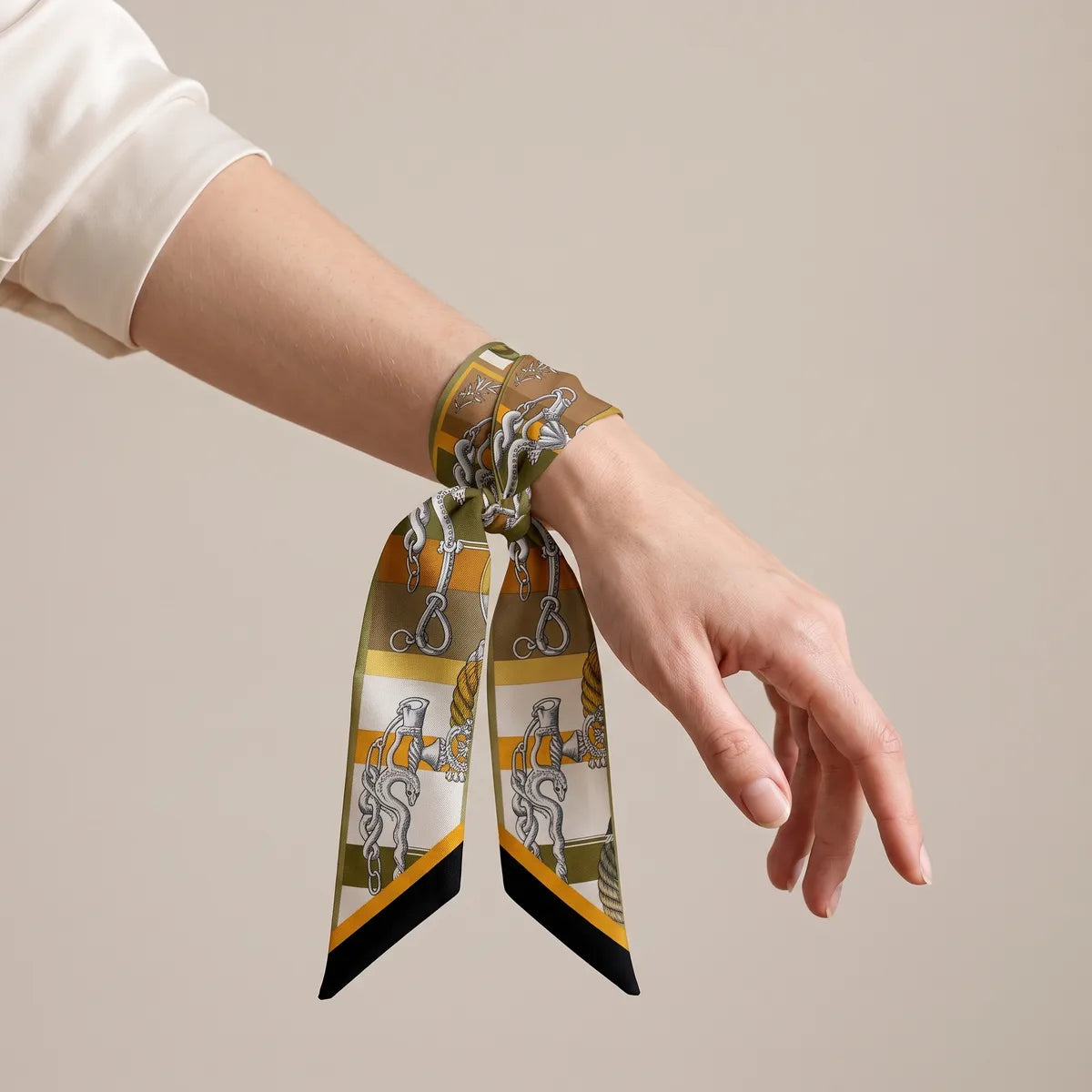 Mustard skinny scarf wrapped around the wrist and tied, chain motifs on the ends