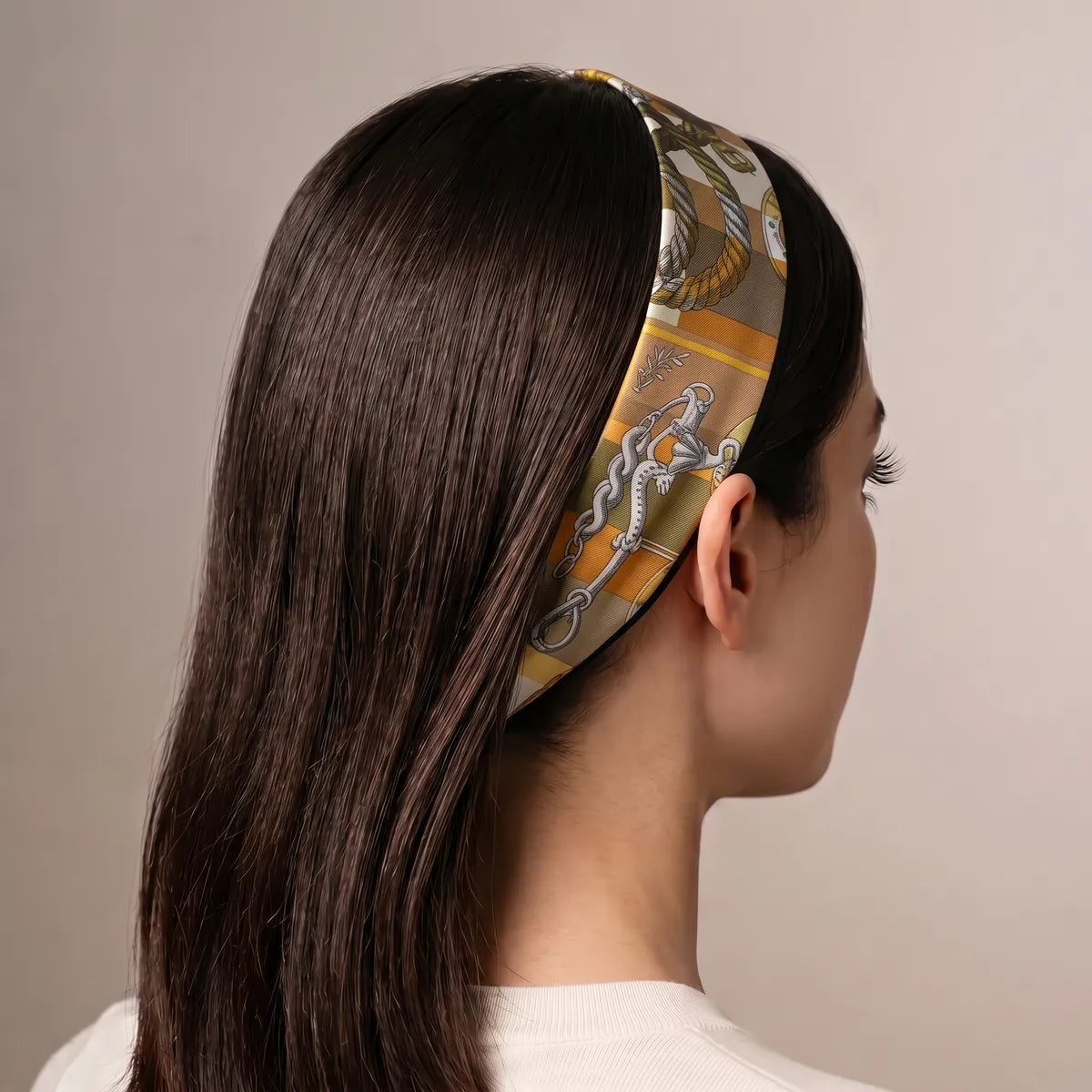 Mustard chain print skinny scarf worn as a headband over long dark hair