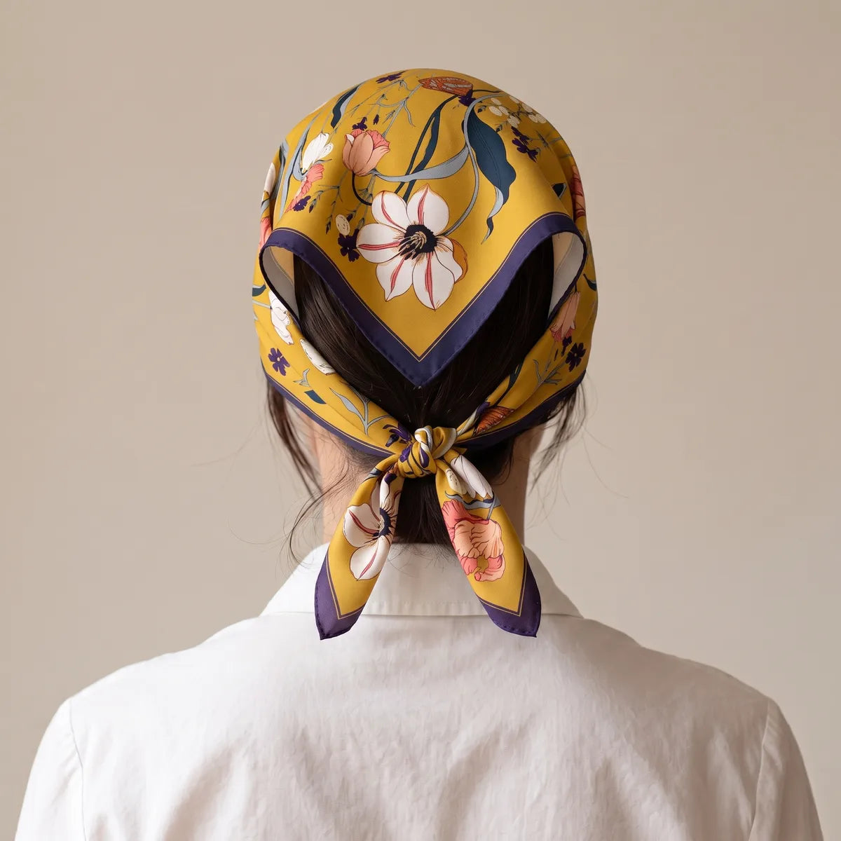 Mustard floral bandana worn over the hair and tied at the nape, seen from behind