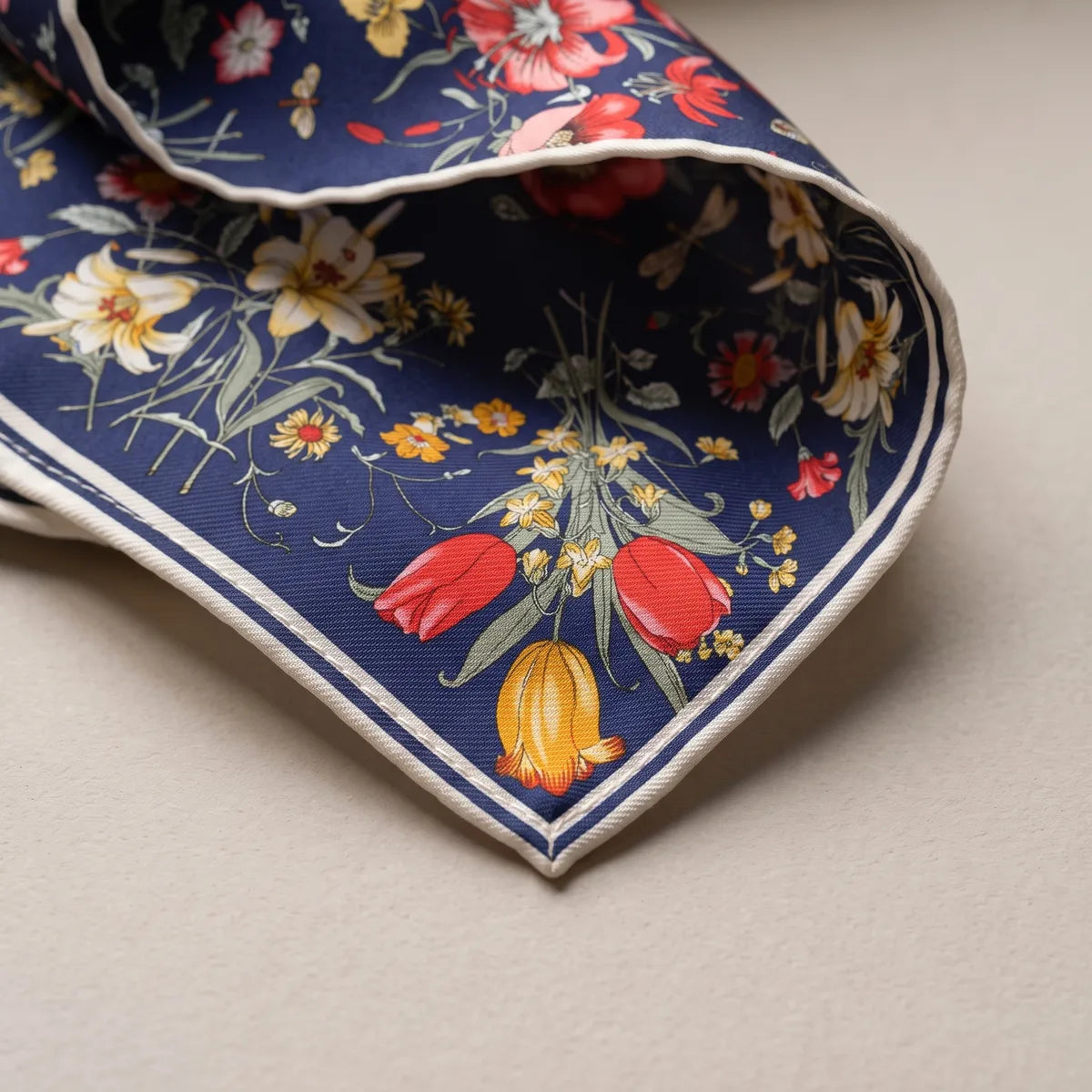 Corner of the navy shawl with red tulips and a yellow tulip above the cream and navy border