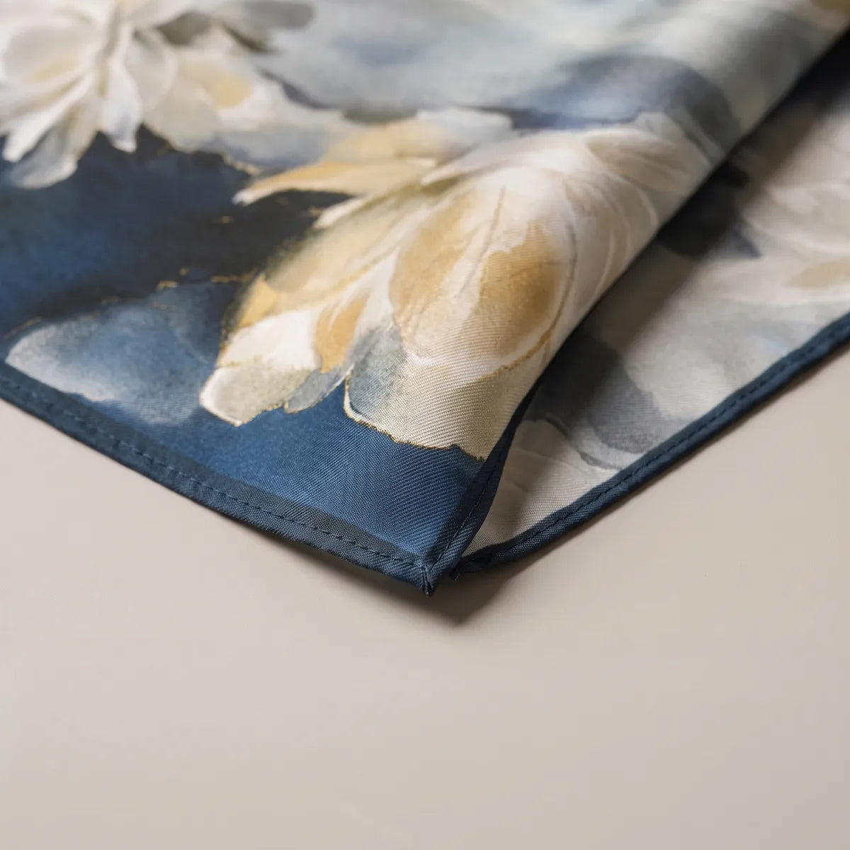 Corner of the painted flower silk bandana: sand-tinted petals, smoky blue wash and the navy hem