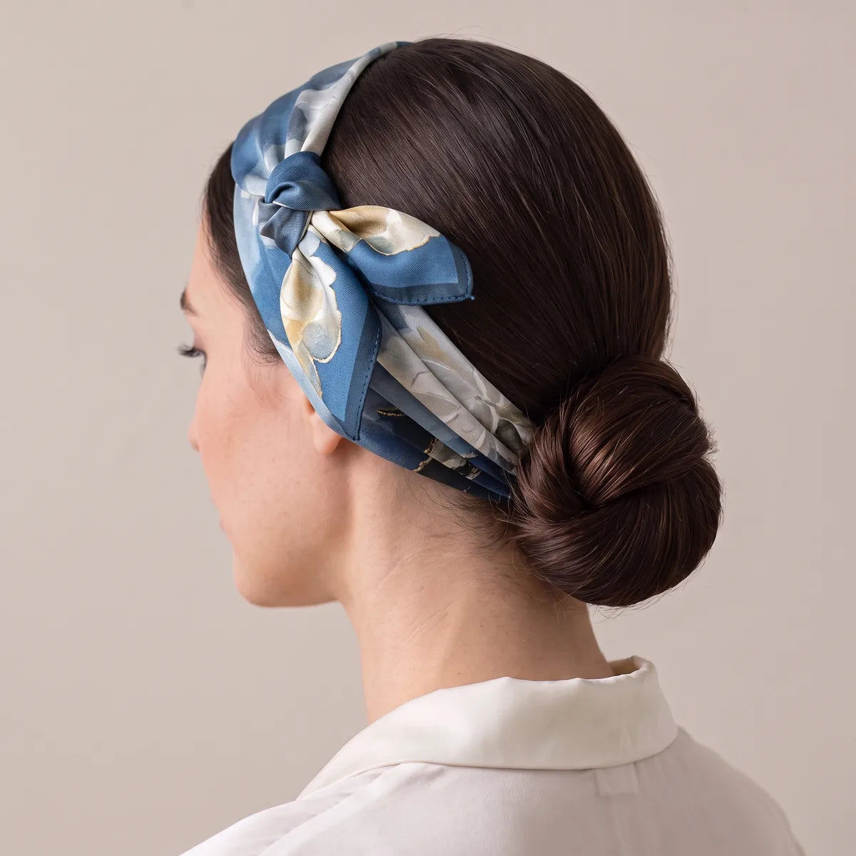 Navy silk scarf with cream flowers folded into a headband, knot above the ear, hair twisted into a bun