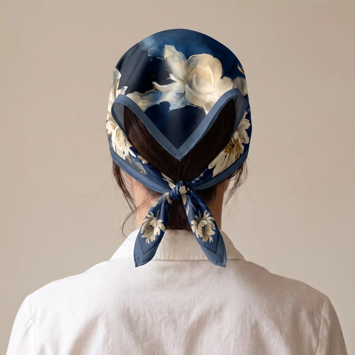 Navy floral kerchief from behind: the border dips into a V on the back of the head, knot resting on the hair at the nape