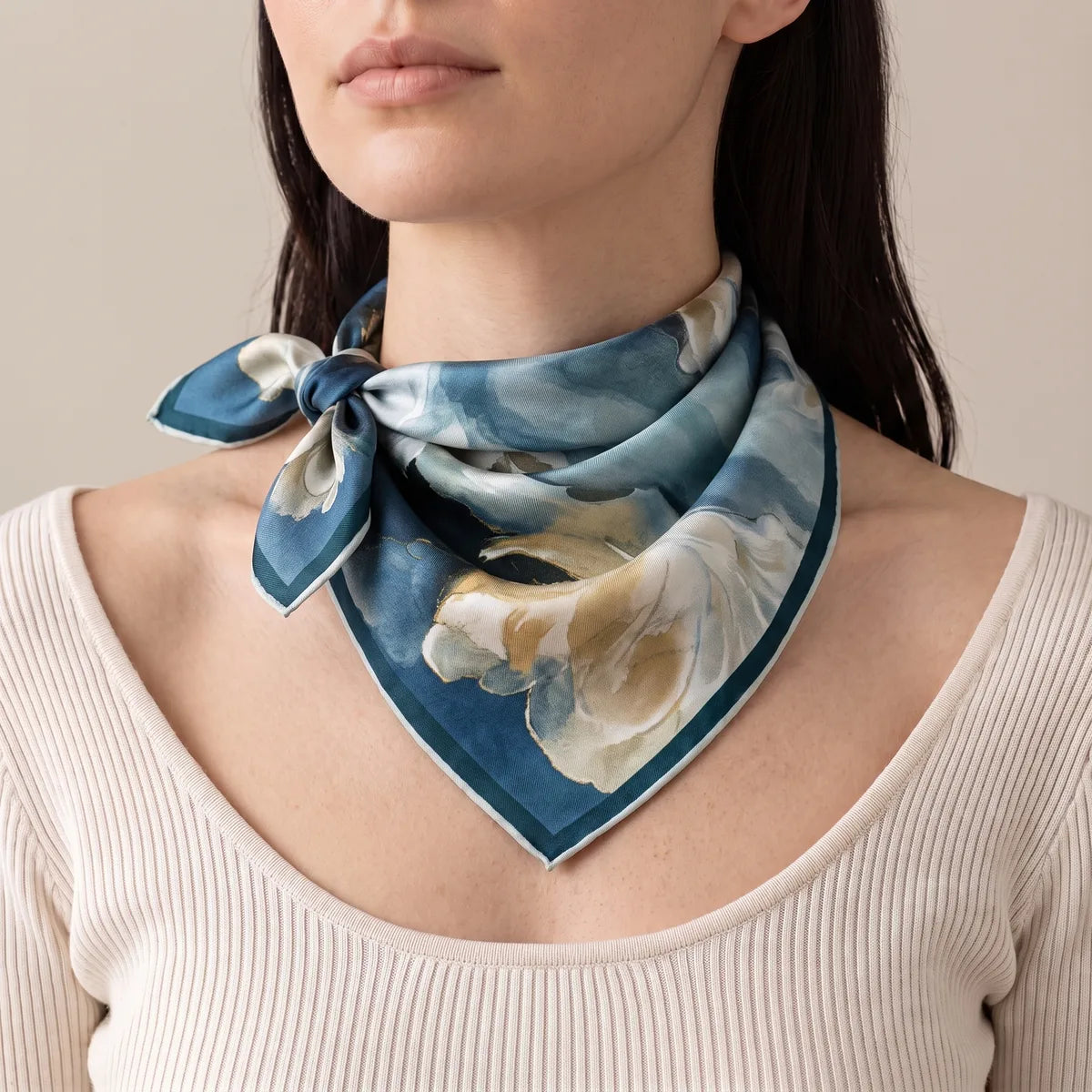 Woman in an ivory ribbed top wearing the navy floral bandana knotted to one side of her neck
