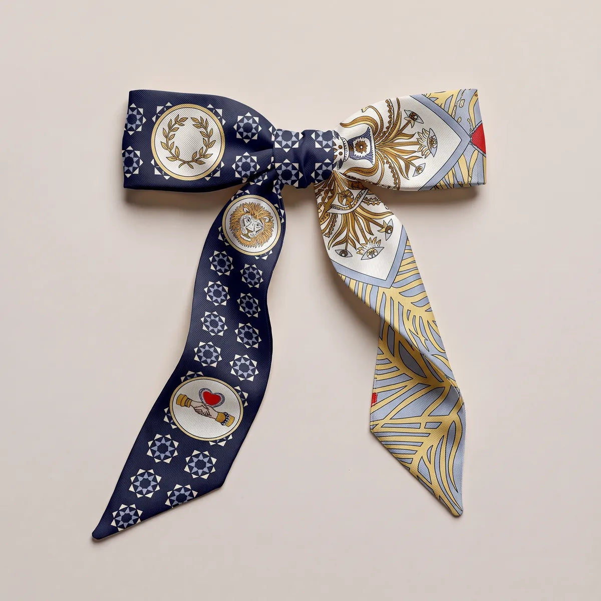 Navy and cream skinny silk scarf tied in a bow, laurel wreath medallion on the left loop