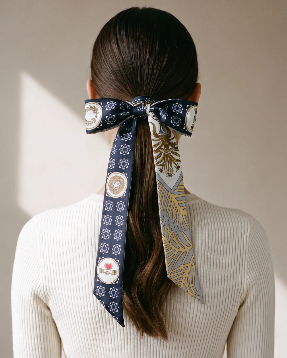 Navy medallion print skinny silk scarf tied in a bow around a ponytail