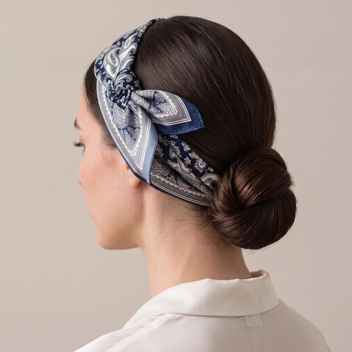Side view of a navy and ivory paisley headband, its knot resting above the ear and one navy tip pointing back