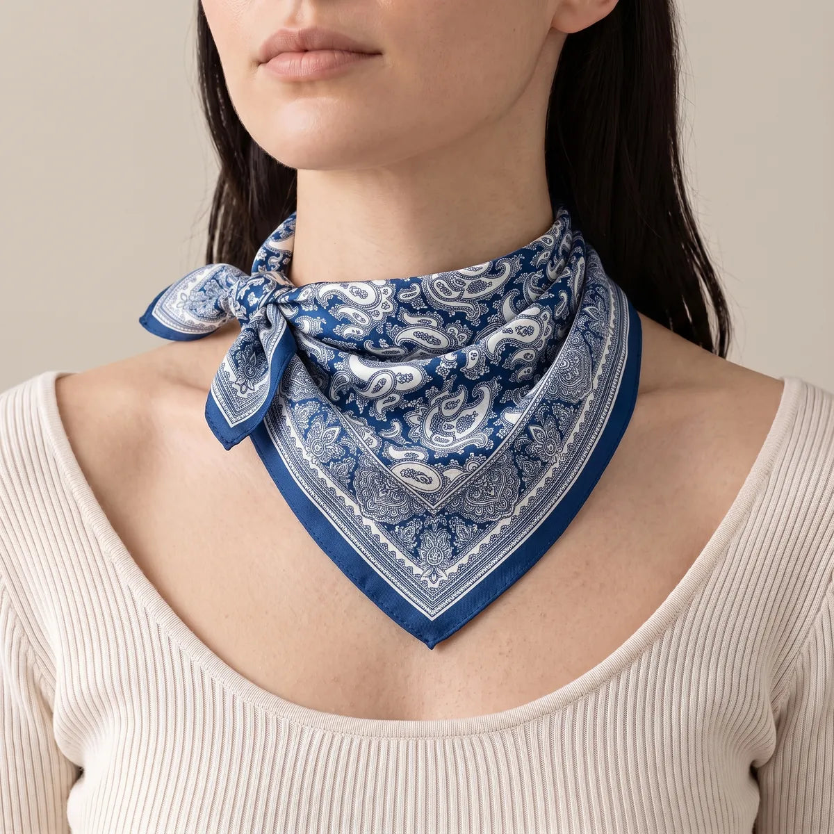 Navy paisley silk bandana tied at one side of the neck, its point hanging in front of a cream ribbed top