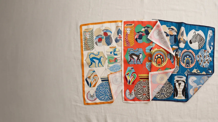 Three colorways of a lantern print silk scarf laid side by side on linen