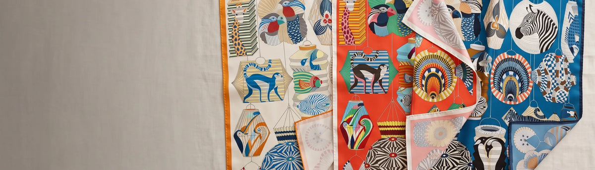 Three colorways of a lantern print silk scarf laid side by side on linen