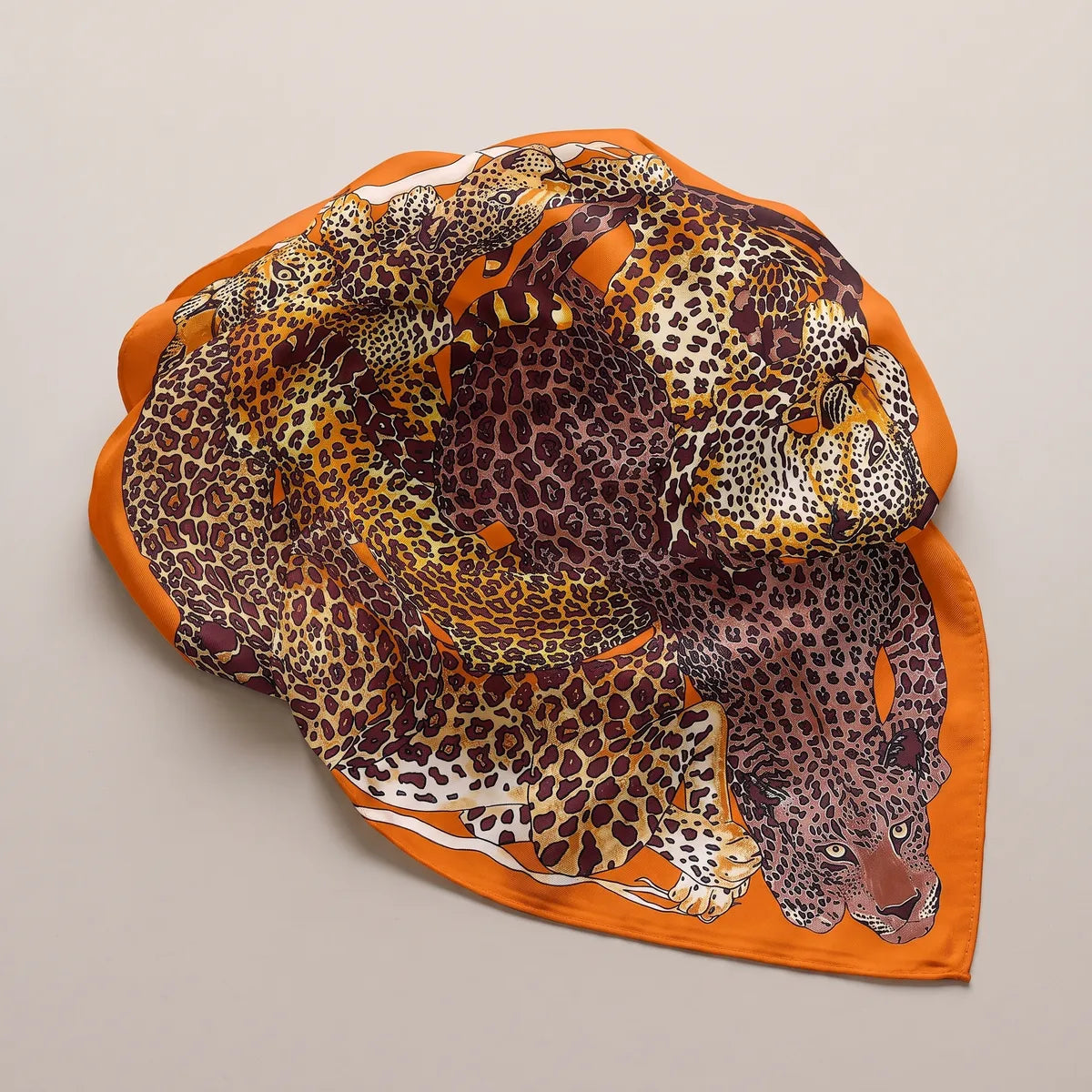 Orange and brown leopard shawl gathered in a soft round, a leopard's head resting near the edge