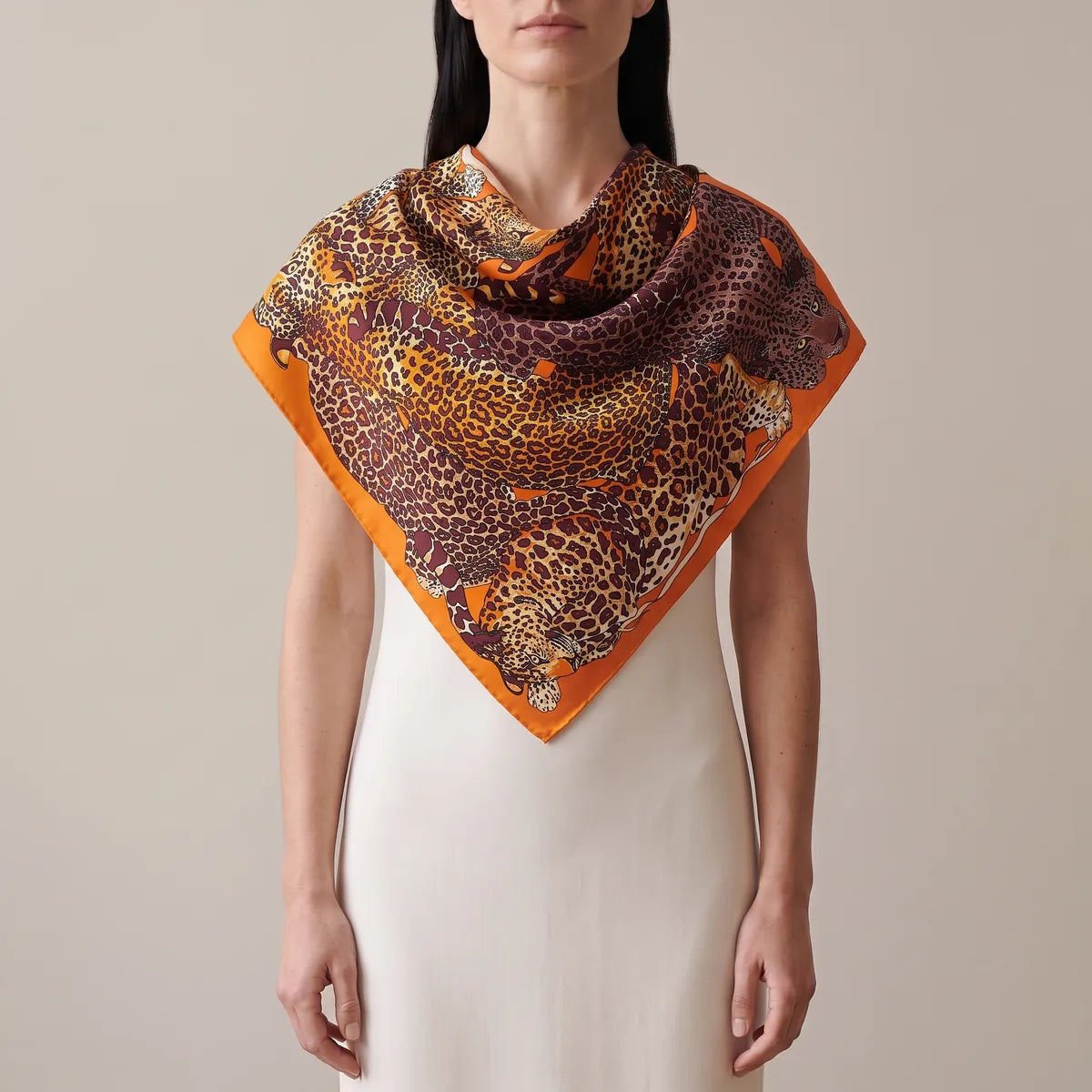 Woman in a cream dress with the orange leopard silk shawl across her shoulders, the border forming a V