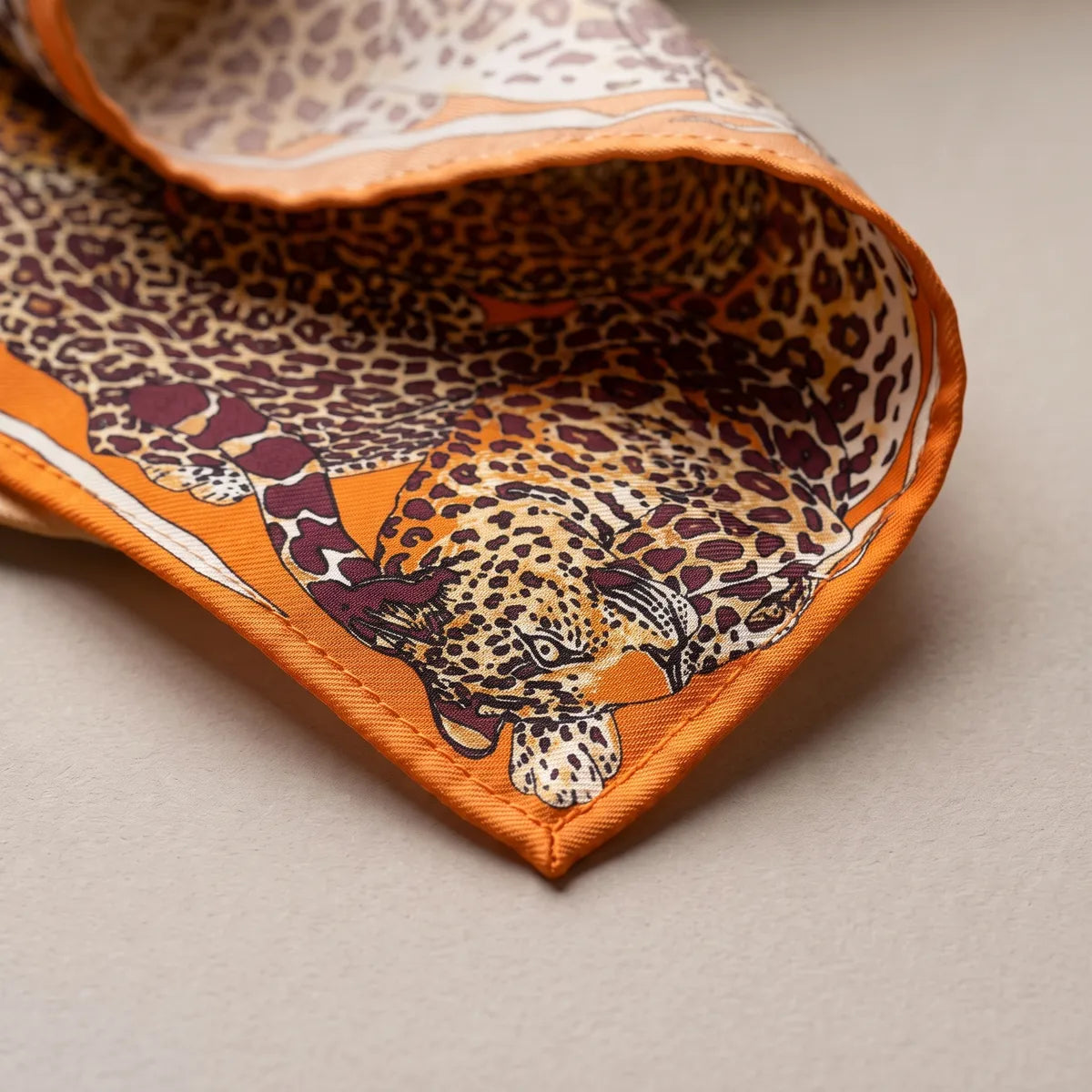 Corner of the orange shawl: a tawny leopard's face and paw beside the orange hem