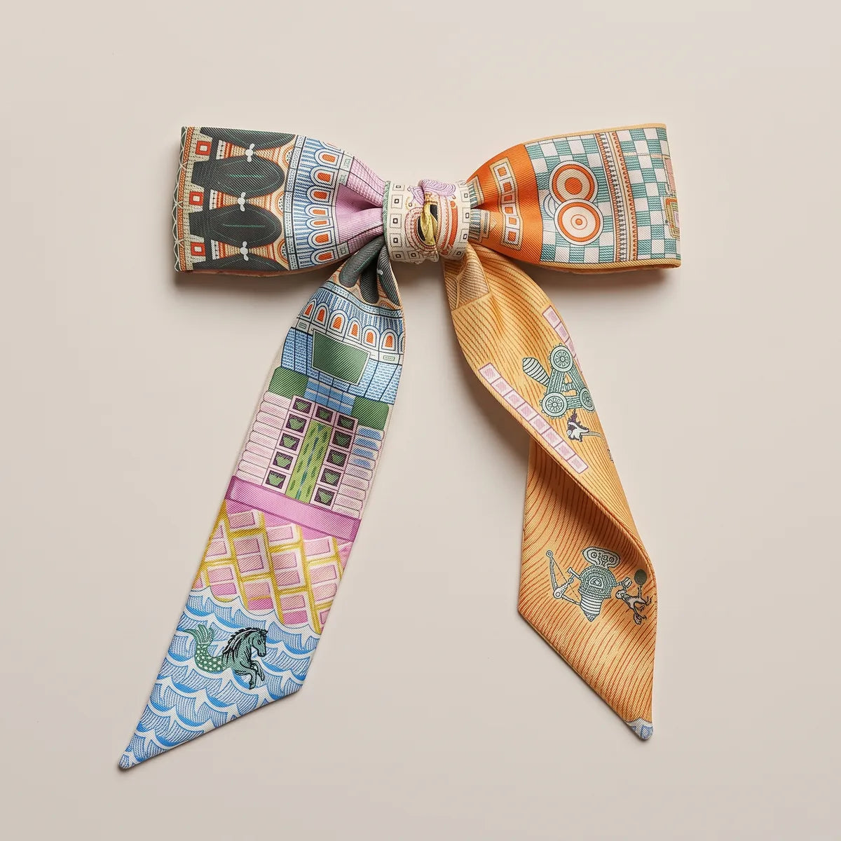 Orange and pink skinny silk and satin scarf tied into a flat bow, orange targets and a teal checkerboard on one loop