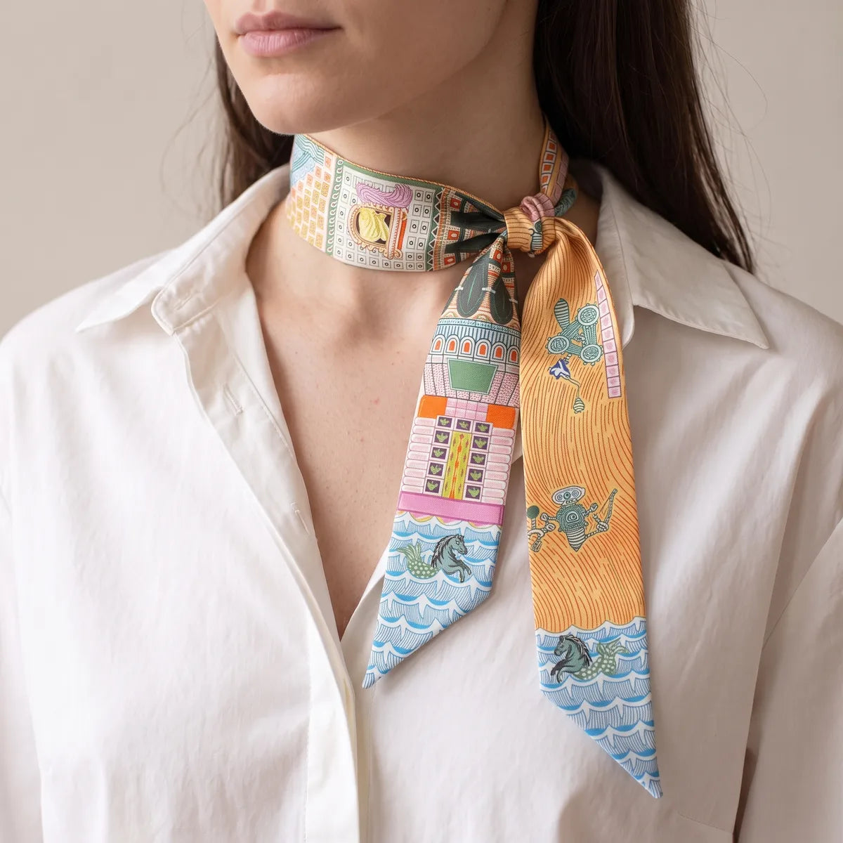 Orange architecture skinny scarf knotted at the side of the neck, the orange and pink strands hanging