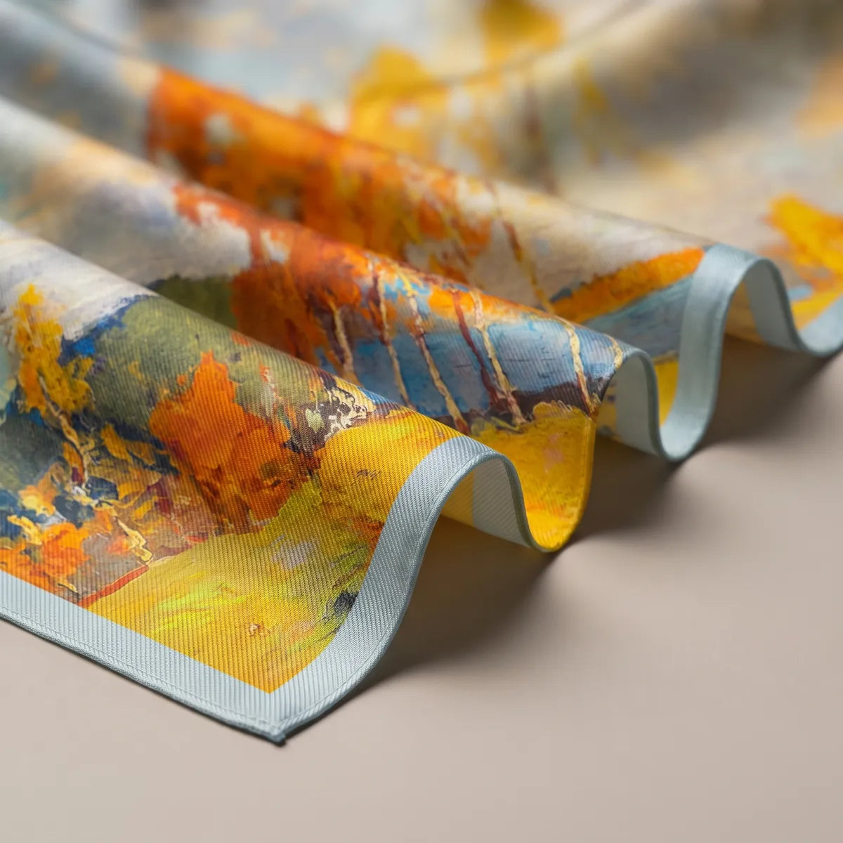 Folds of the painted scarf: white birch trunks, orange leaves, a blue river and the pale aqua hem