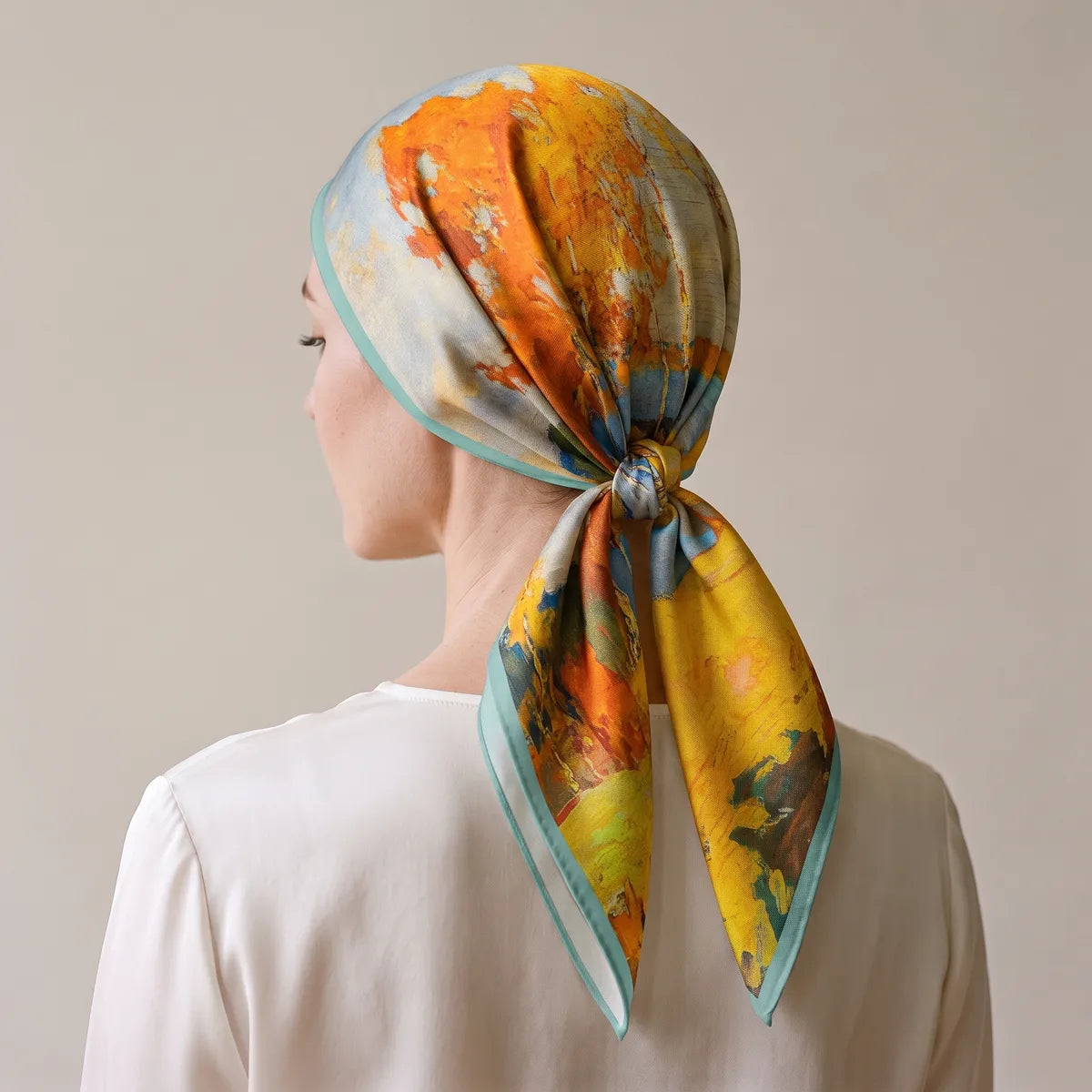Back view: the orange and yellow landscape silk scarf covers the hair, knotted at the nape