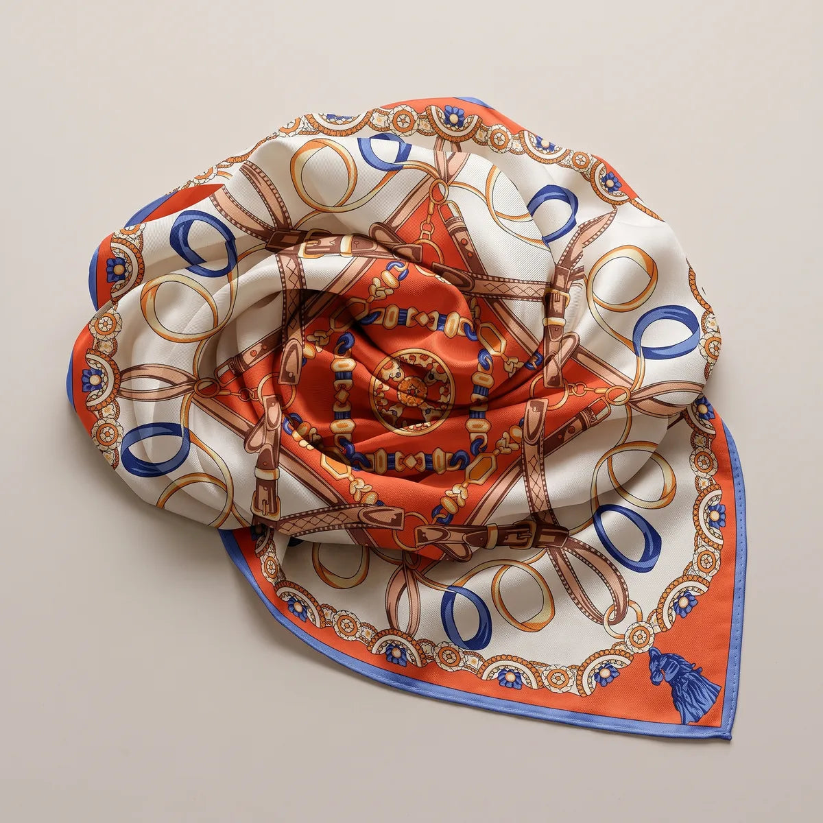 Orange and cream silk shawl swirled into a rosette, straps and loops curling around the center