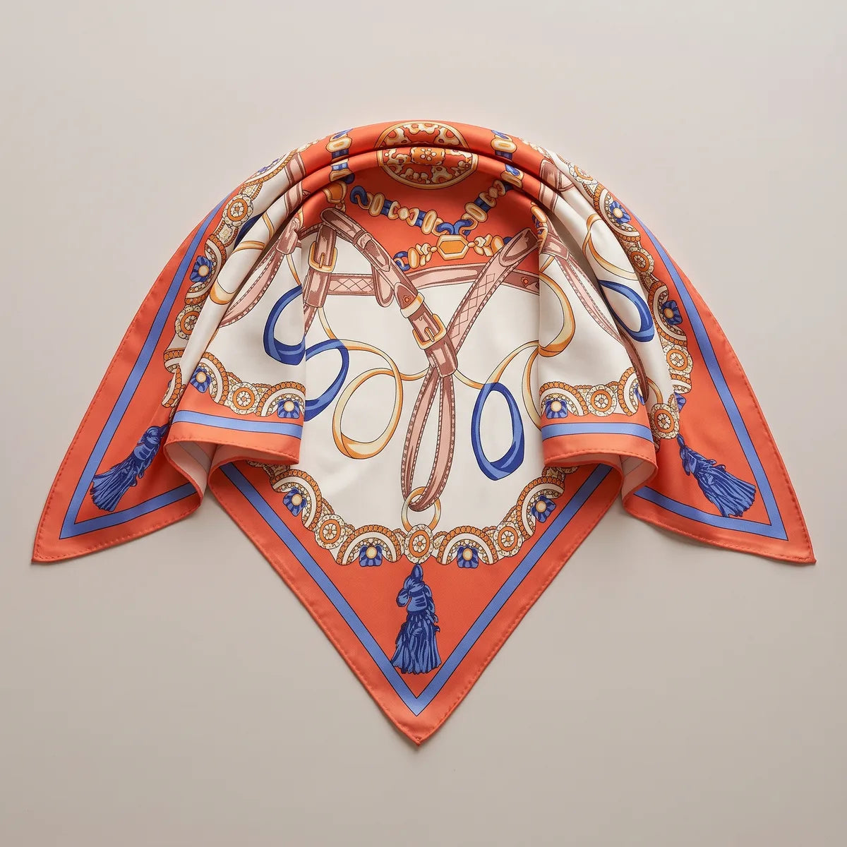 Silk shawl with an orange chain print folded into a triangle, a blue horse-head tassel at the lower point