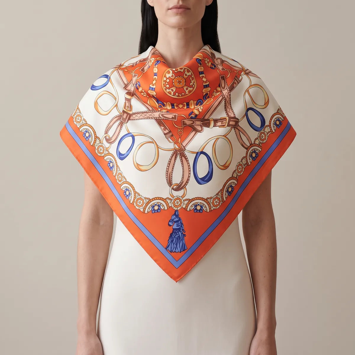 Woman wearing an orange chain print silk shawl draped over the shoulders, the tasseled point at the front