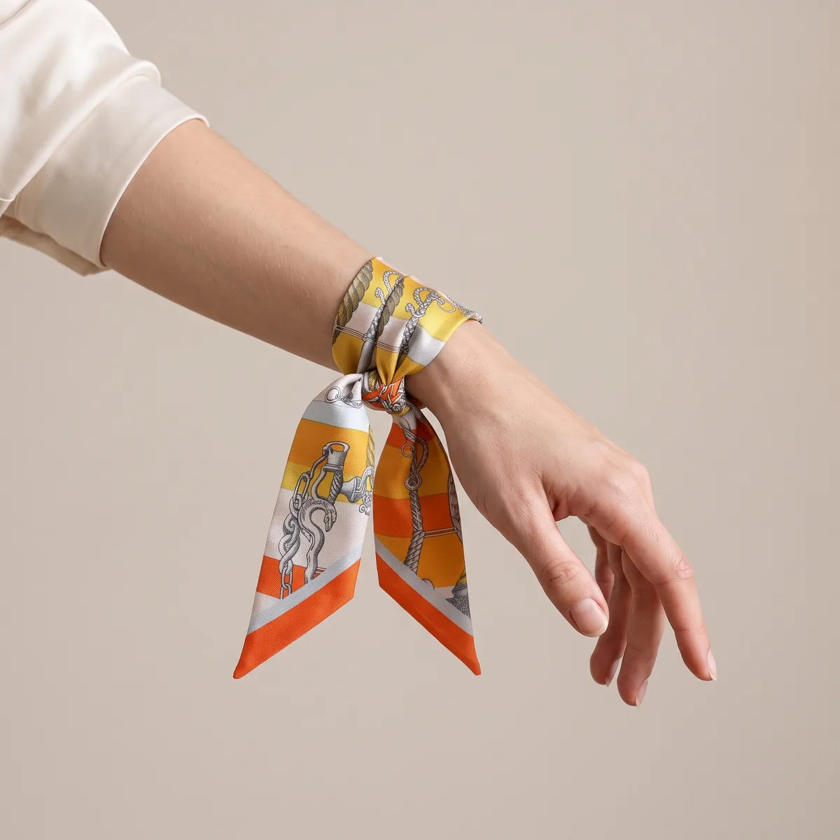 Orange and yellow skinny scarf tied around the wrist, chain motif on the end