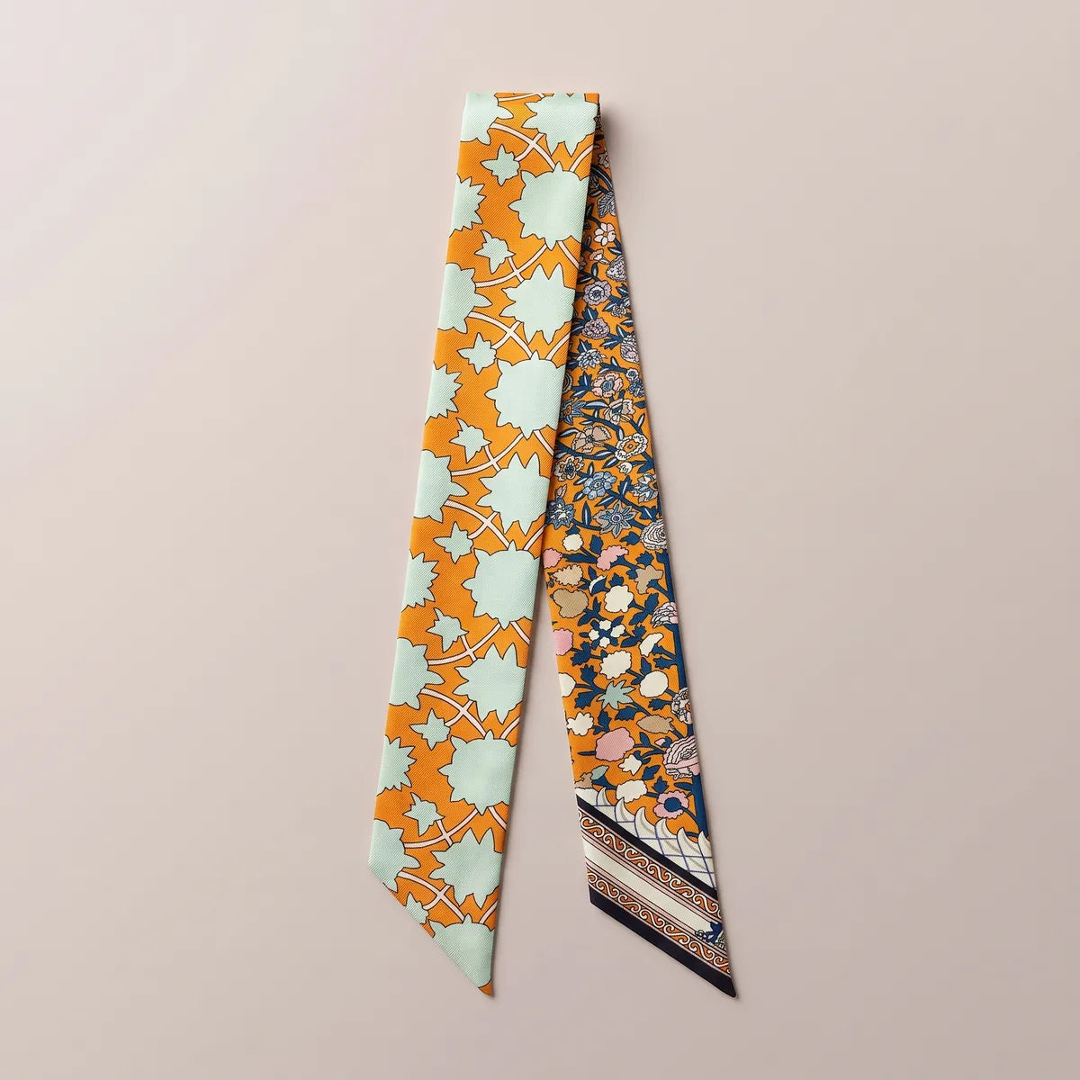 Orange floral skinny silk scarf laid flat: mint star-shaped leaves on one strand, navy and blush flowers on the other
