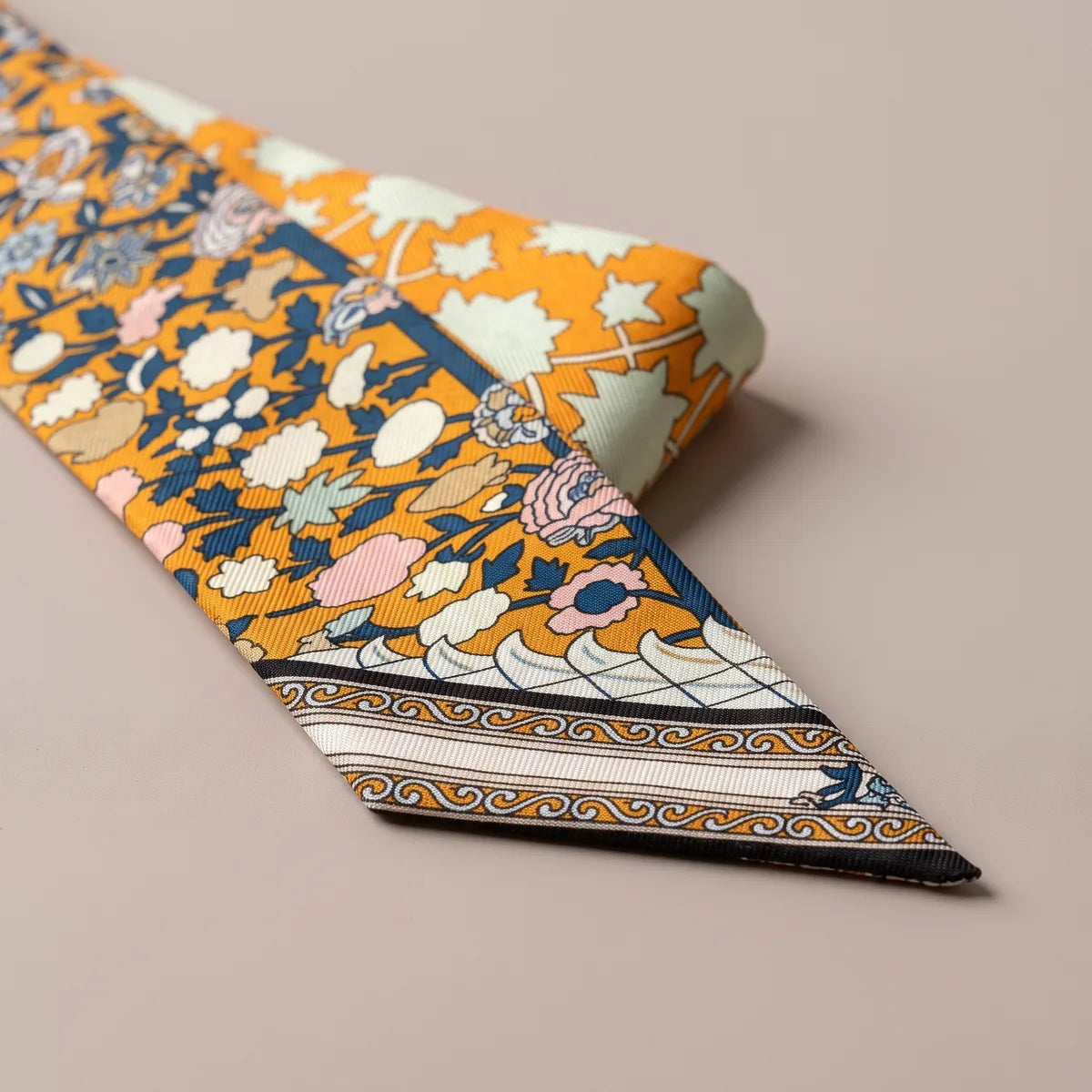 Slanted tip of the orange skinny scarf: scroll and wave band, then cream and navy stripes