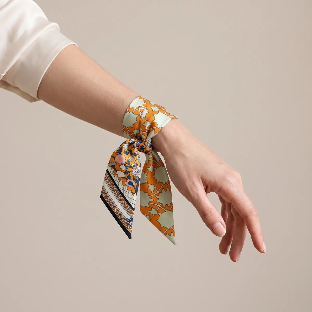 Orange skinny silk scarf with mint stars tied around the wrist like a bracelet