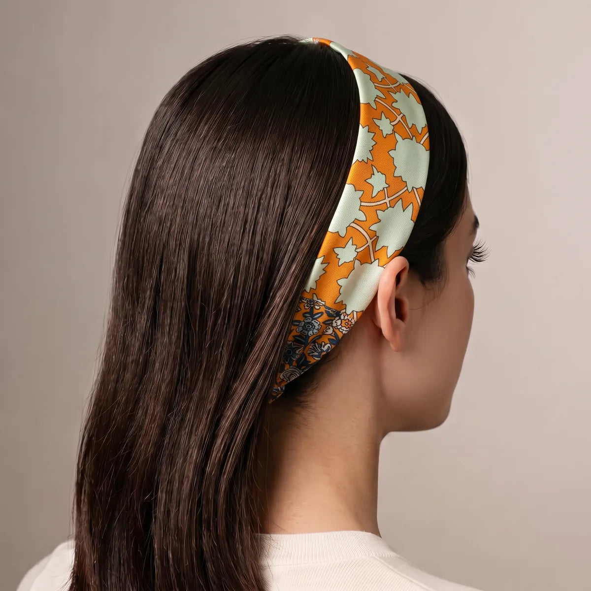 Orange floral skinny scarf as a headband over long dark hair, seen from behind, mint stars along the top