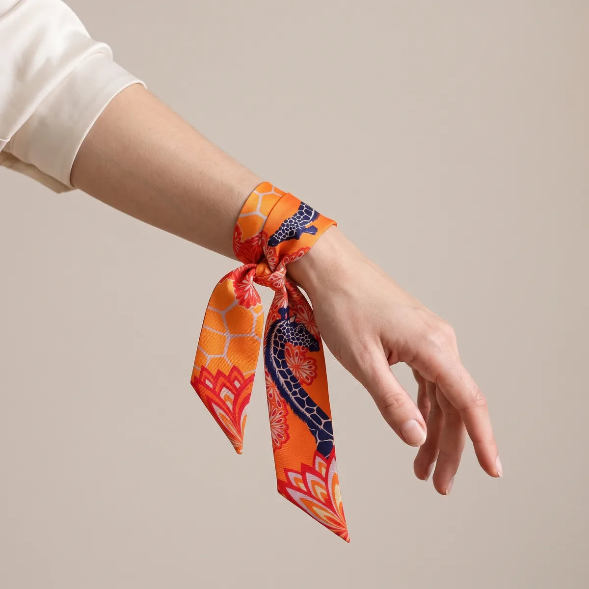 Orange giraffe print skinny scarf wrapped around the wrist and knotted
