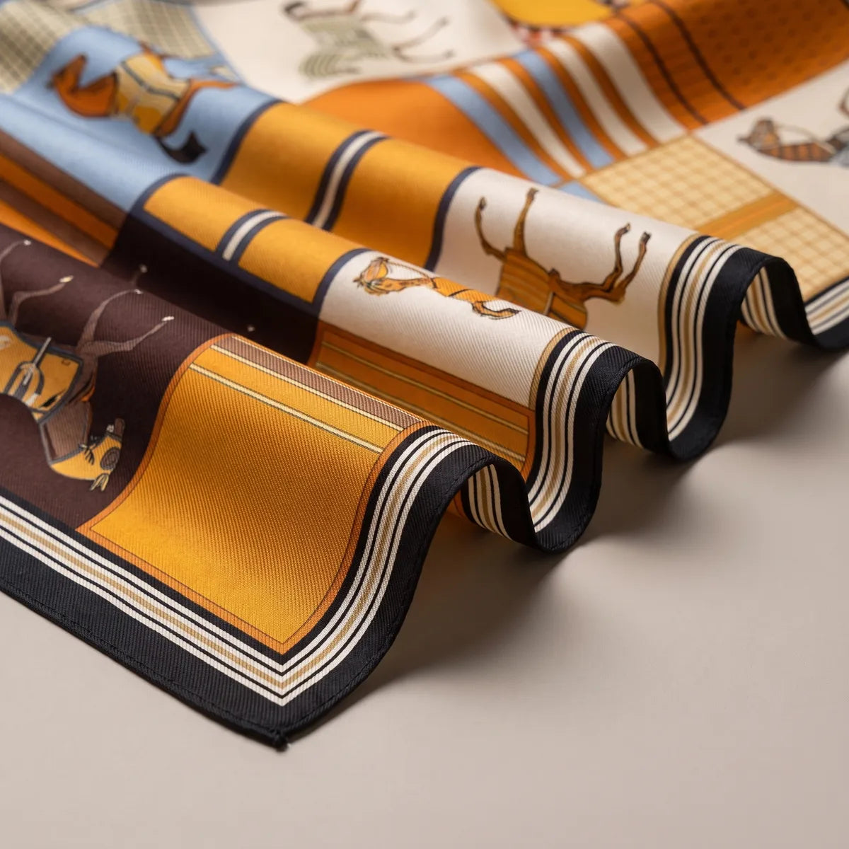 Close-up of a horse print silk scarf in soft folds, showing the cream border, fine stripes and black edge