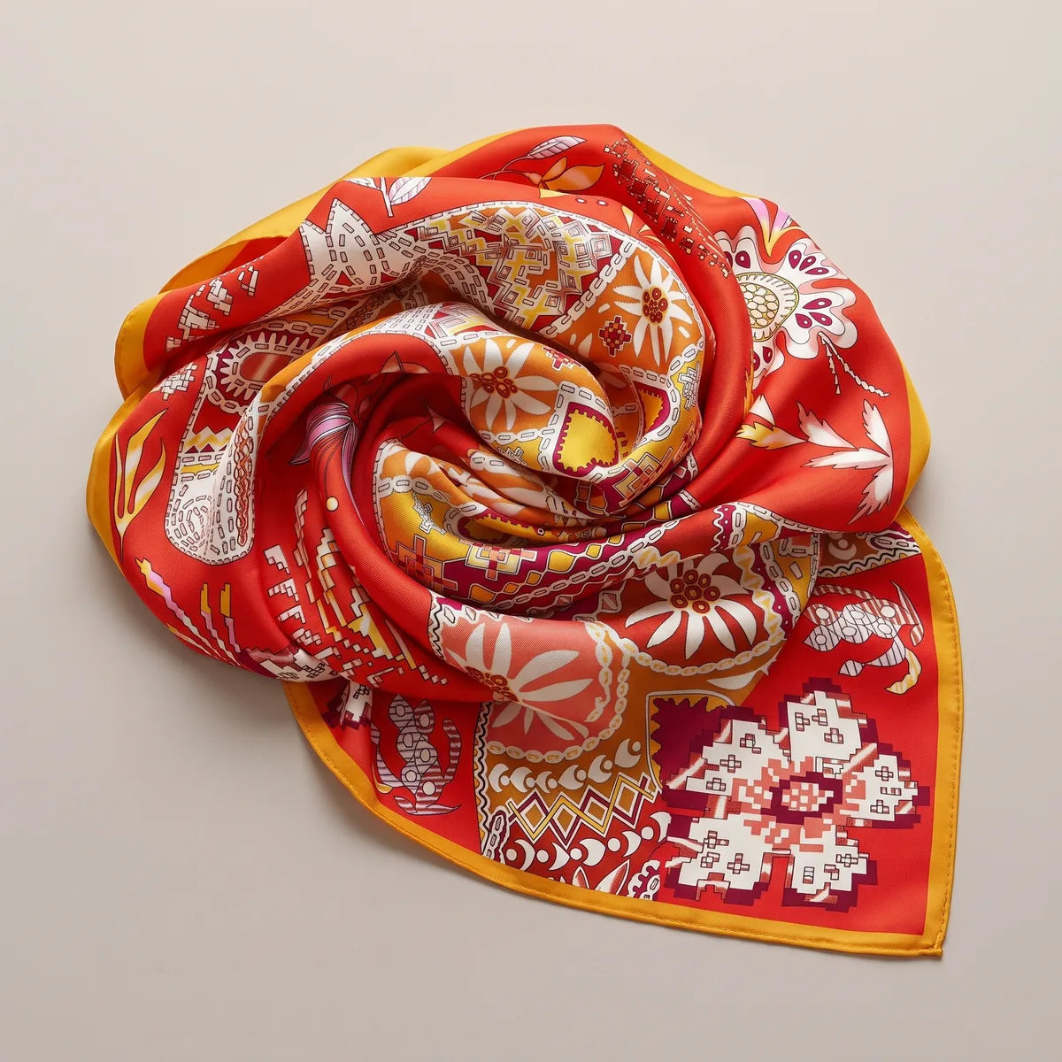 Orange patchwork shawl twisted into a rosette, red cross-stitch flowers and yellow hearts curling around it