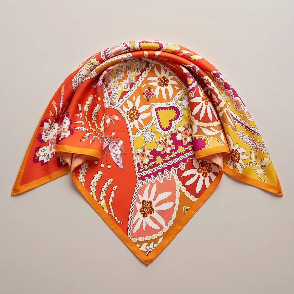 Orange and red folk print silk shawl folded into a triangle, a daisy panel at the point and a saffron edge